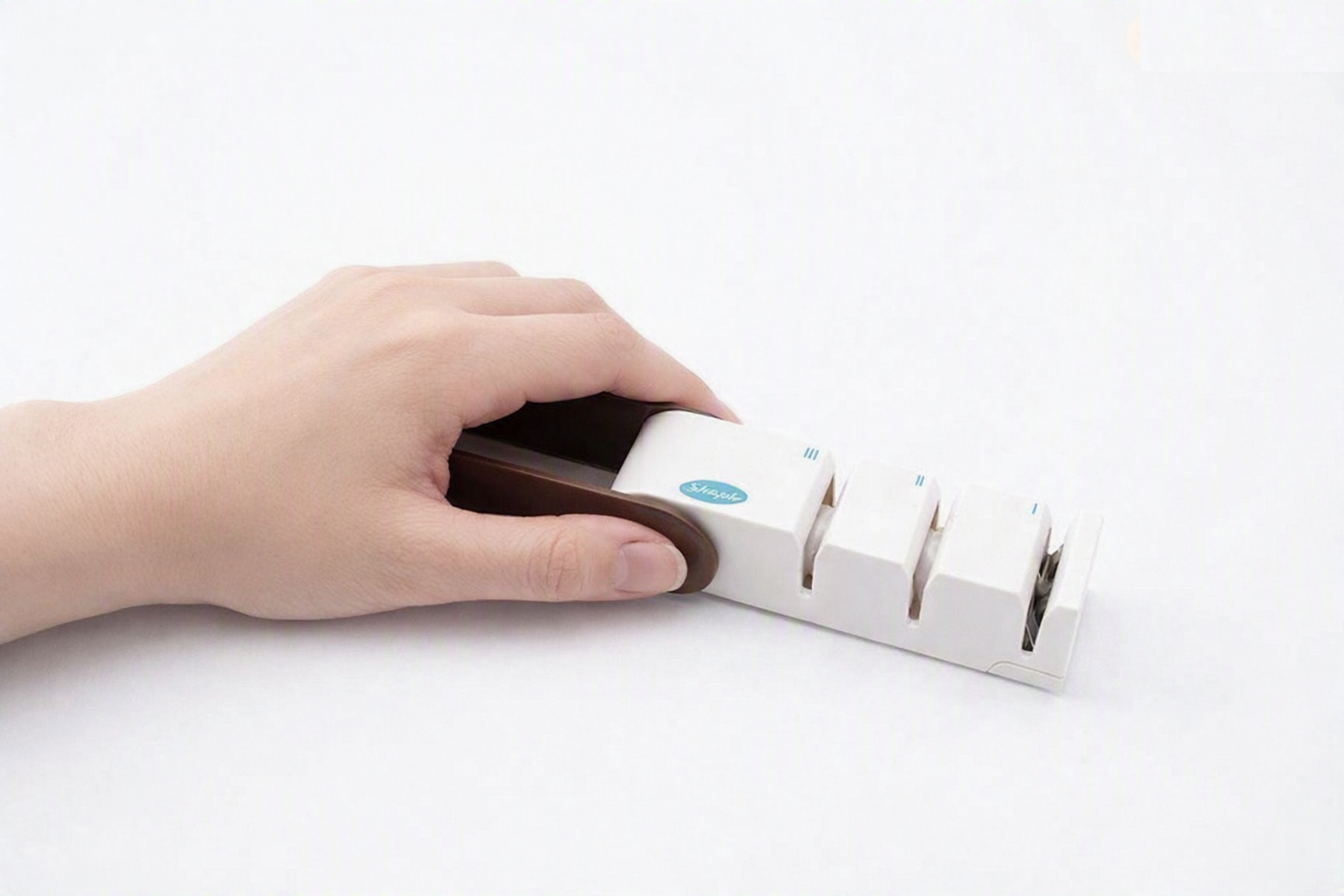 Gripping the sharpener handle firmly on a flat surface